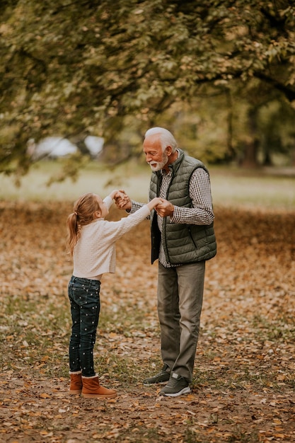 Grand-père passe du temps avec sa petite-fille dans le parc le jour de l'automne