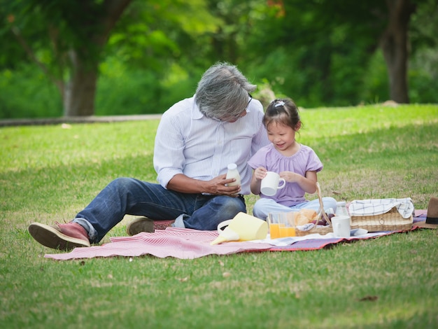 Le grand-père passe le temps en vacances avec ses petits-enfants au parc naturel.