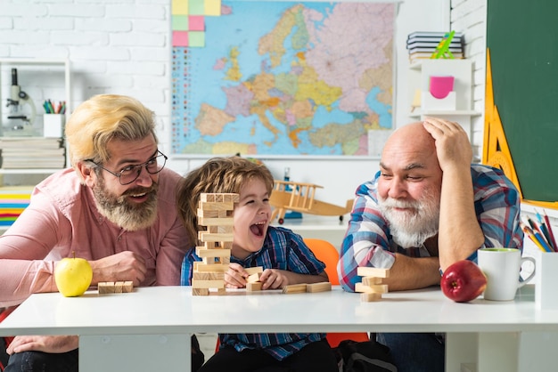 Grand-père père et fils jouant au jeu de jenga à la maison homme heureux famille s'amuser ensemble père et ...