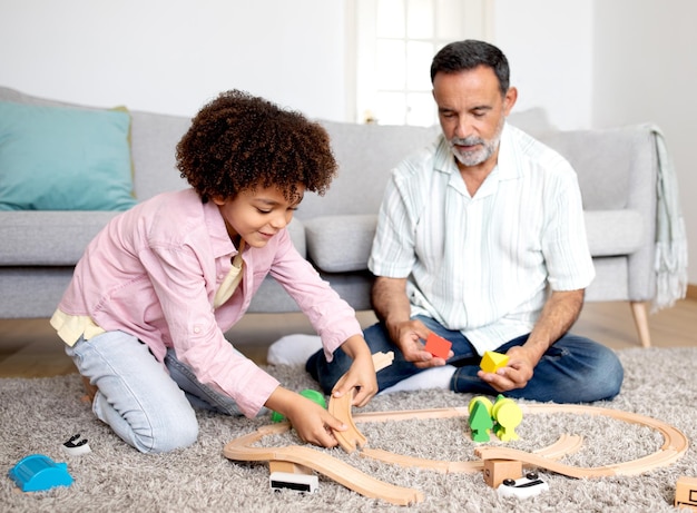 Photo grand-père et petit-fils se lient et jouent avec des jouets à la maison