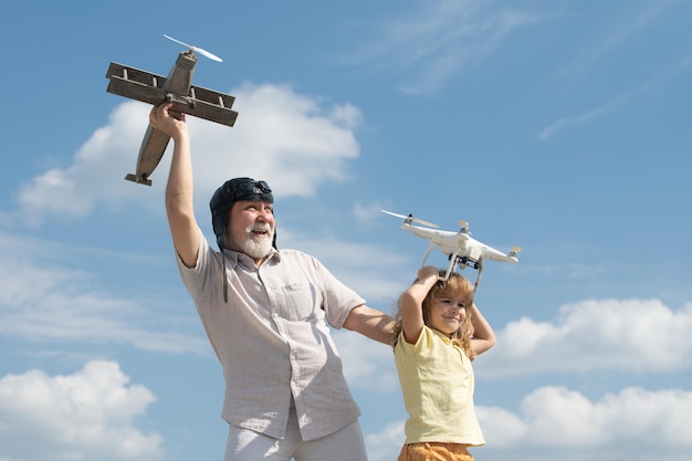 Grand-père et petit-fils tiennent avion et drone quad copter contre ciel enfant pilote aviateur avec avion...