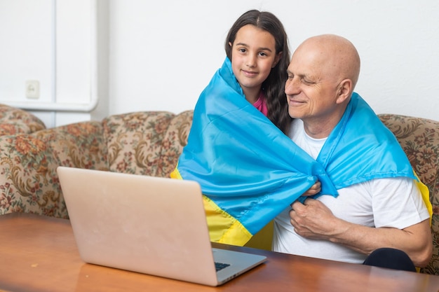 Grand-père et petite-fille avec ordinateur portable et drapeau de l'Ukraine