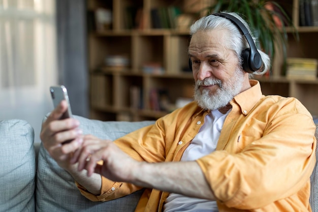 Grand-père positif utilisant un casque sans fil et un téléphone portable