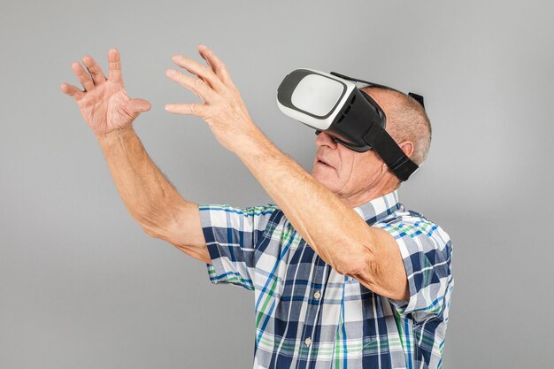 Grand-père se penche sur les gestes de la main des lunettes VR sur fond gris