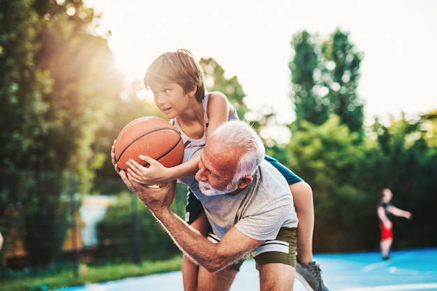Grand-père et son petit-fils s'amusant ensemble sur un terrain de basket.