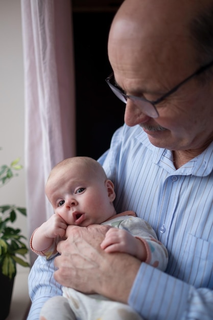 Grand-père tenant une belle petite fille nouveau-née à la maison