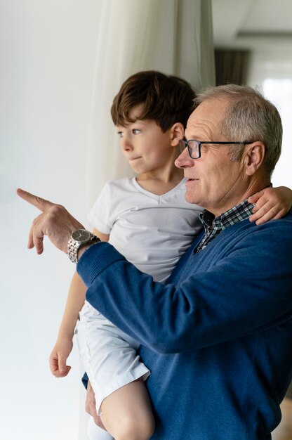 Photo grand-père tenant son petit-fils près de la fenêtre