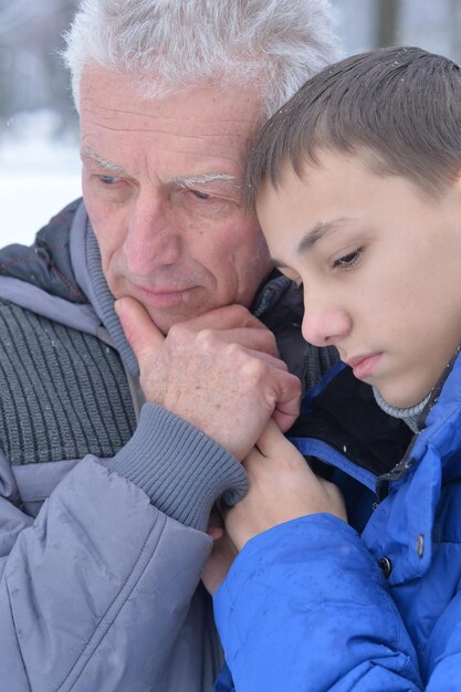 Grand-père triste avec petit-fils ensemble, posant dehors en hiver