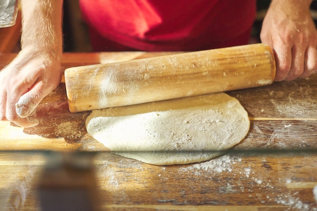 Grand plan, de, mâle, boulanger, mains, à, farine, cuisinier, dérouler la pâte avec rouleau à pâtisserie