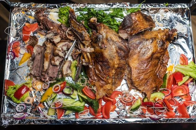 Photo grand plateau avec du porc au four et des légumes frais