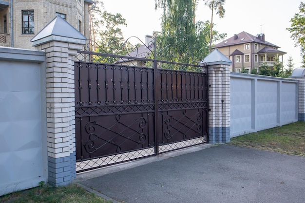 Grand portail privé moderne en fer forgé marron de la maison. Idées de design et de décoration pour la maison. Porte en fer pour clôture de jardin. Façade d'une maison dans une rue de la ville.