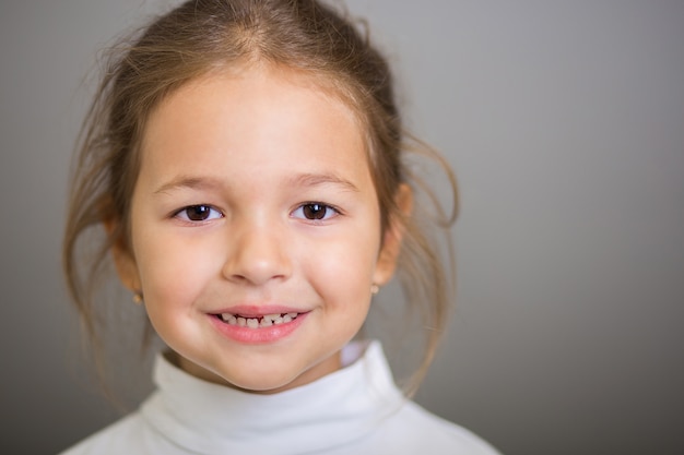 Grand portrait de la jeune fille souriante aux dents de lait tombées