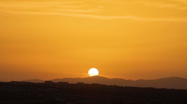 Grand soleil au coucher du soleil se cachant derrière les montagnes Ciel de couleur dorée Espace de copie