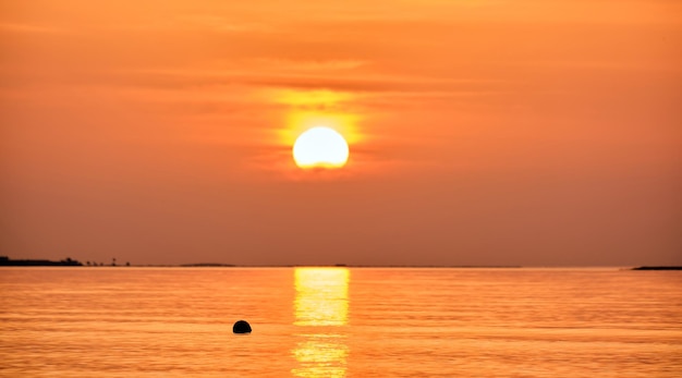 Grand soleil jaune se couchant sur la surface de la mer.