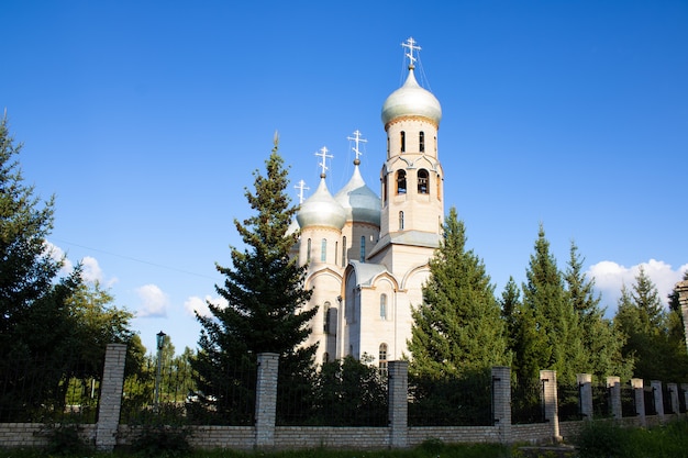 Un grand temple de pierre blanche avec des dômes contre un ciel bleu et des conifères