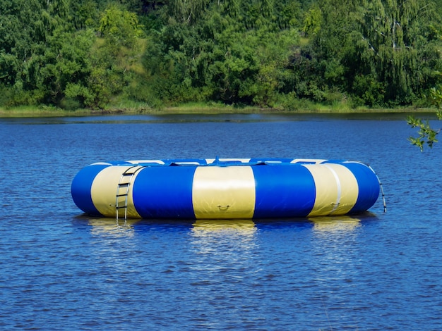 Grand trampoline bleu rond gonflable un jour ensoleillé d'étang