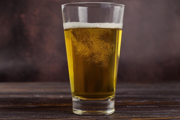 un grand verre de bière légère froide avec de la mousse sur un fond sombre StPatrick s Day