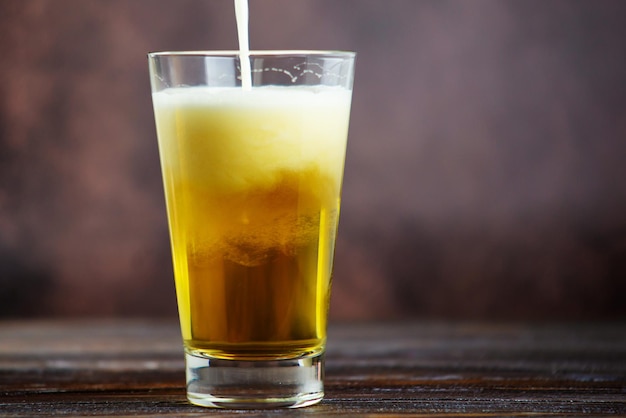 un grand verre de bière légère froide avec de la mousse sur un fond sombre StPatrick s Day