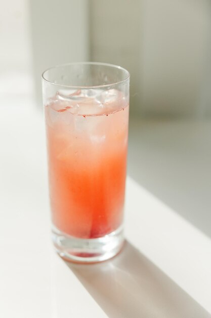 Un grand verre rempli de jus d'orange et d'un cube de glace