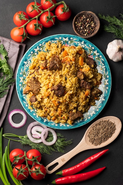 Une grande assiette remplie de pilaf à côté de zéros de tomates cerises, d'ail frais et d'un mélange