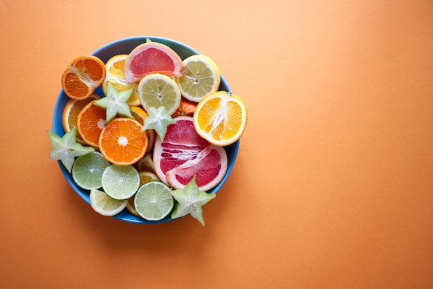 Grande assiette avec tranches d'agrumes sur fond orange