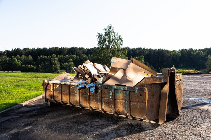 Grande benne à ordures pleine de carton contre forêt