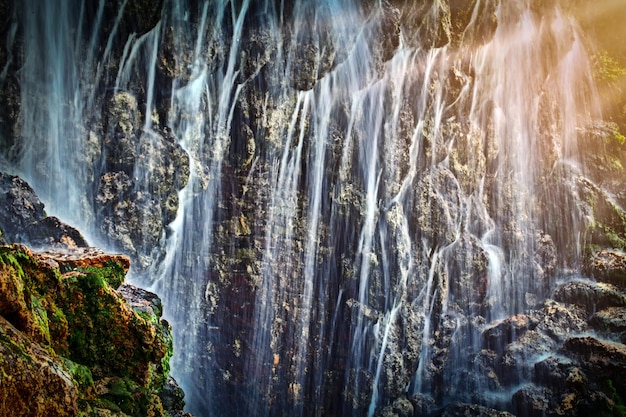 Une grande cascade dans une grotte sous les rayons du soleil