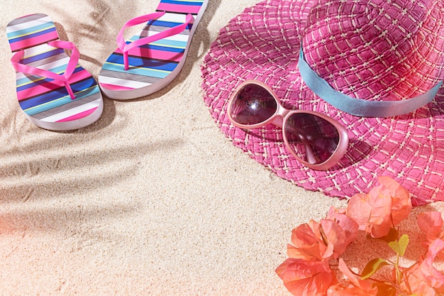 Grande chaleur rose d'été ronde, avec lunettes de soleil et tongs sur le sable de la plage, vue de dessus, espace pour copie