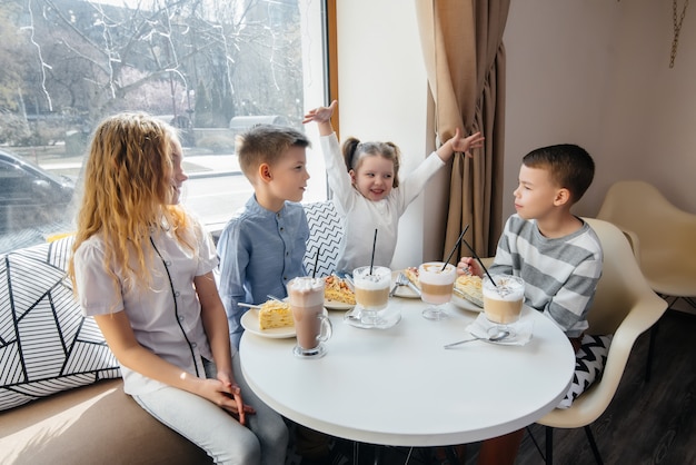 Une grande compagnie amicale d'enfants fête les vacances dans un café avec un délicieux dessert. Le jour de la naissance.