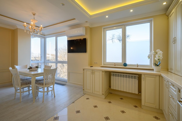 Grande cuisine classique blanche et beige avec table à manger dans un studio