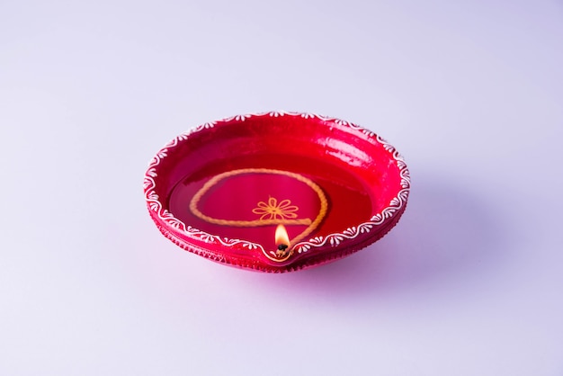 Grande diya décorative en argile rouge ou lampe à huile allumée pendant le festival de diwali. Mise au point sélective