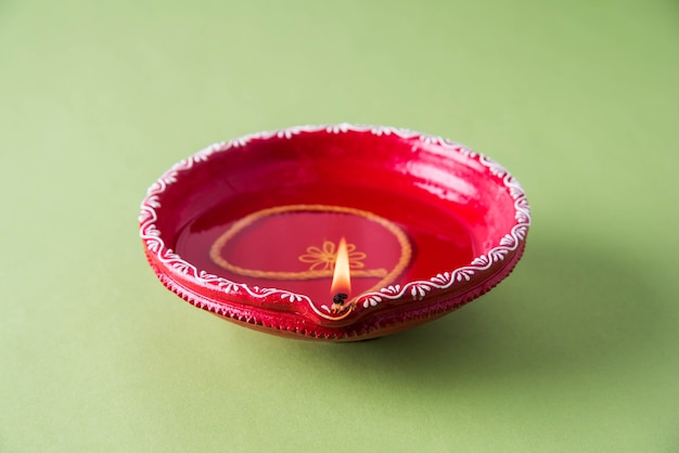 Grande diya décorative en argile rouge ou lampe à huile allumée pendant le festival de diwali. Mise au point sélective