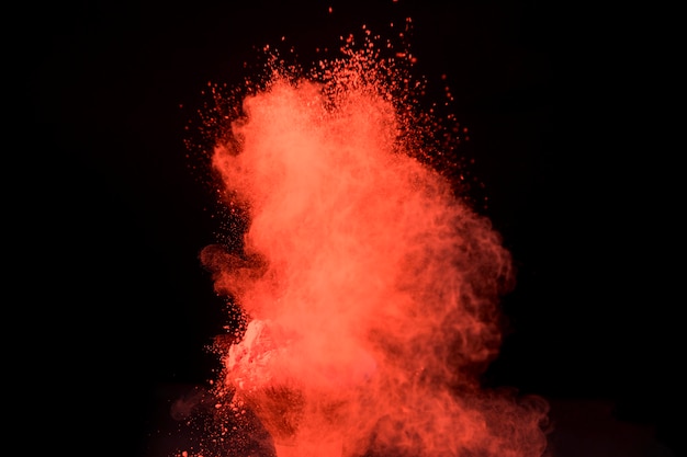 Photo grande explosion rouge de poudre sur fond sombre