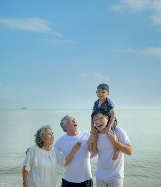 Une grande famille asiatique voyage ensemble sur la plage. Âge de la retraite avec fils et petits-enfants relaxants et récréatifs pendant les vacances d'été.