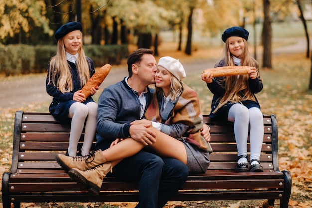 Une grande famille est assise sur un banc dans un parc d'automne Des gens heureux dans le parc d'automne