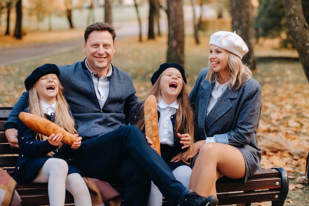Une grande famille est assise sur un banc dans un parc d'automne Des gens heureux dans le parc d'automne