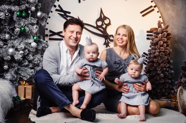 Une grande famille heureuse avec des enfants jumeaux à l'intérieur de la maison du Nouvel An dans le contexte d'une grande horloge.