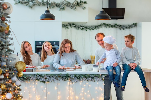 Grande famille heureuse faisant du pain d'épice, coupant des biscuits de pâte de pain d'épice, s'amusant. Nourriture festive, processus de cuisson, concept de cuisine familiale, de traditions de Noël et du nouvel an. Boulangerie de Noël.