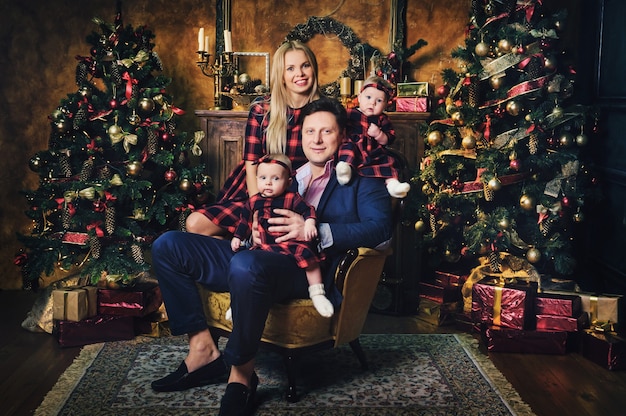 Une grande famille heureuse avec leurs enfants à l'intérieur de la maison du Nouvel An près de la cheminée à côté de l'arbre de Noël