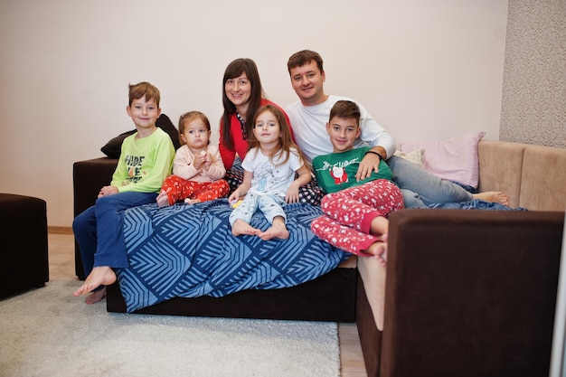 Une grande famille heureuse s'amuse ensemble dans la chambre. Grand concept de matinée en famille. Quatre enfants avec des parents portent un pyjama au lit à la maison.