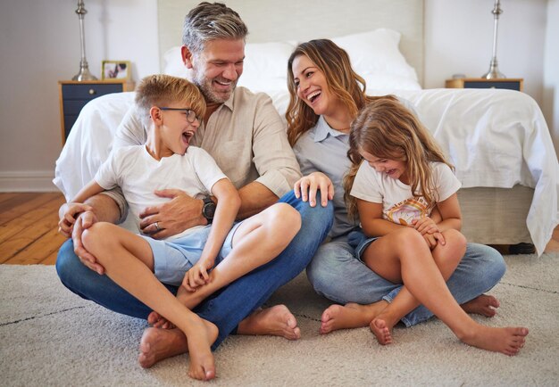 Grande famille heureuse et souriante avec du temps de qualité à la maison dans une chambre avec des enfants Bonheur de la mère et des enfants riant d'une blague amusante sur le sol de la maison avec joie et amour des parents