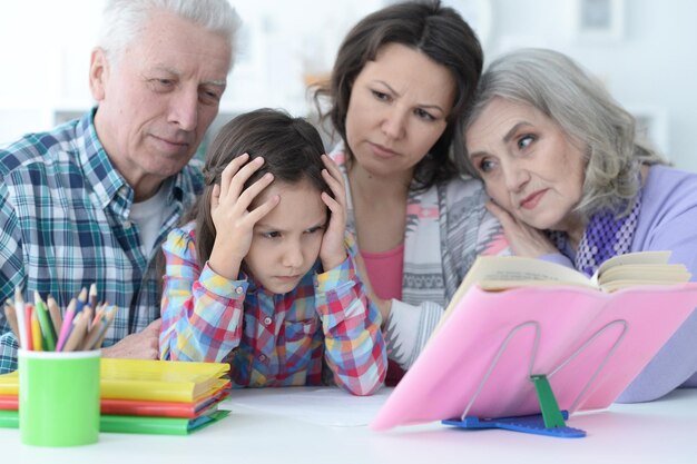 Grande famille avec une jolie petite fille faisant ses devoirs ensemble