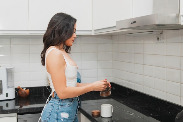 Grande fille préparant un café du matin dans la cuisine de sa maison