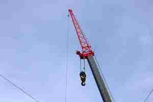 Photo grande grue à bras de construction avec crochet lourd sur câble métallique dans un ciel bleu clair