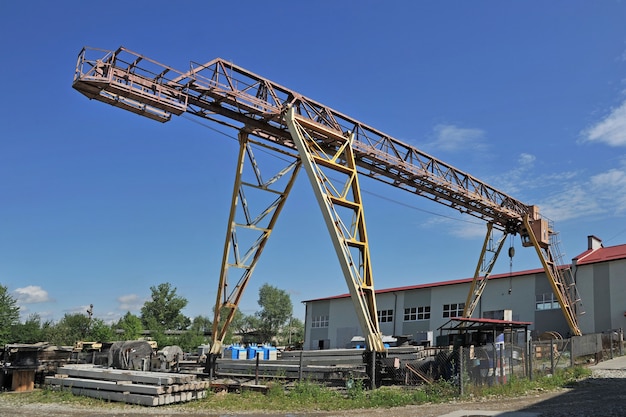 Grande grue à portique sur fond de bâtiments d'entrepôt et d'un ciel bleu vif