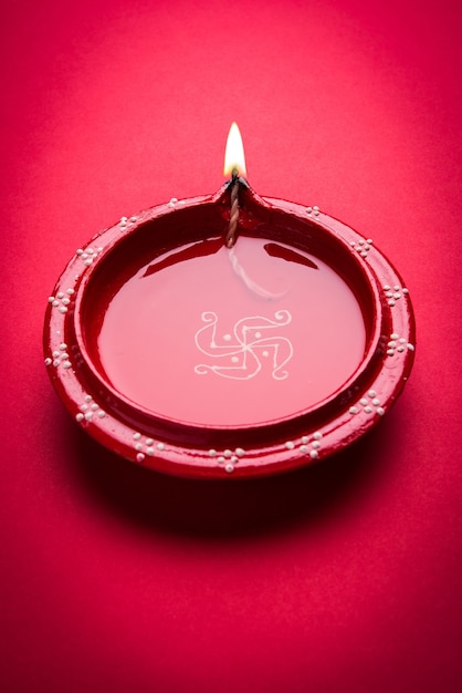 Grande lampe diwali diya ou argile illuminée placée sur une surface rouge, éclairage de mauvaise humeur, mise au point sélective