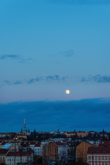 Photo une grande lune au-dessus de la ville avec un ciel bleu et des nuages