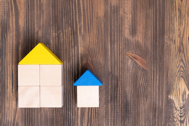 Grande et petite maison avec toit jaune et bleu fait de cubes de jouets en bois sur une vue de dessus de fond en bois marron