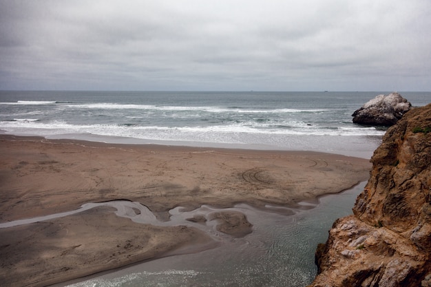 Grande plage déserte, belle vue sur l'océan, grosses pierres