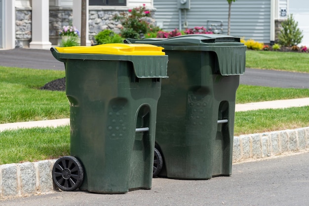 Photo grande poubelle en plastique verte vide devant la maison moderne